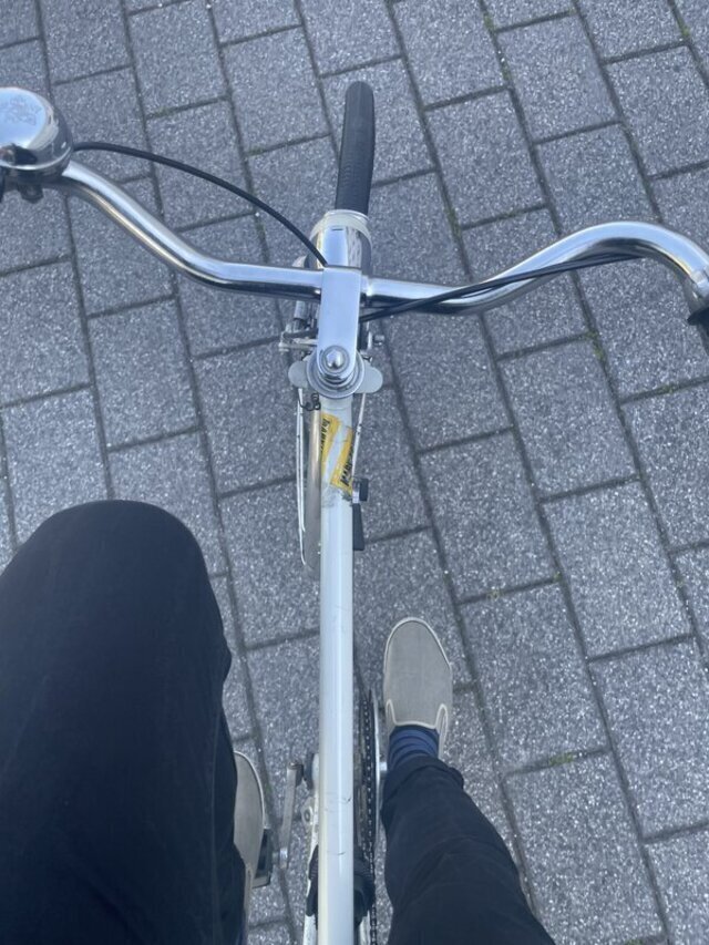 Herr Montag auf dem Rad, man sieht seine Schuhe, gestreifte Socken, den Lenker und etwas Boden