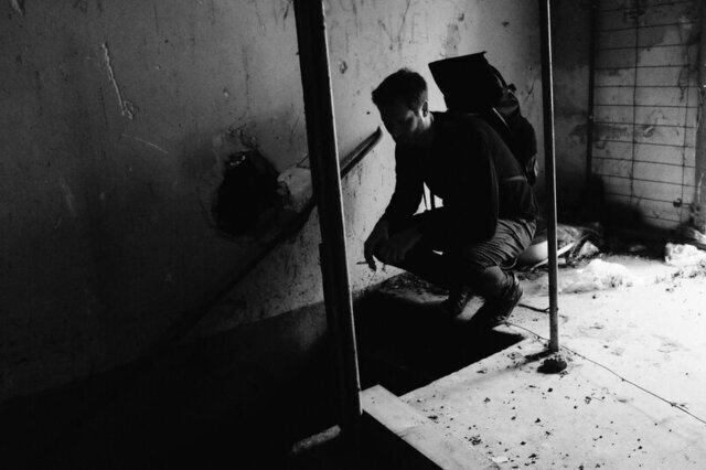 Herr Montag in einem Lost Place, er ist gekauert und blickt eine Treppe hinab.